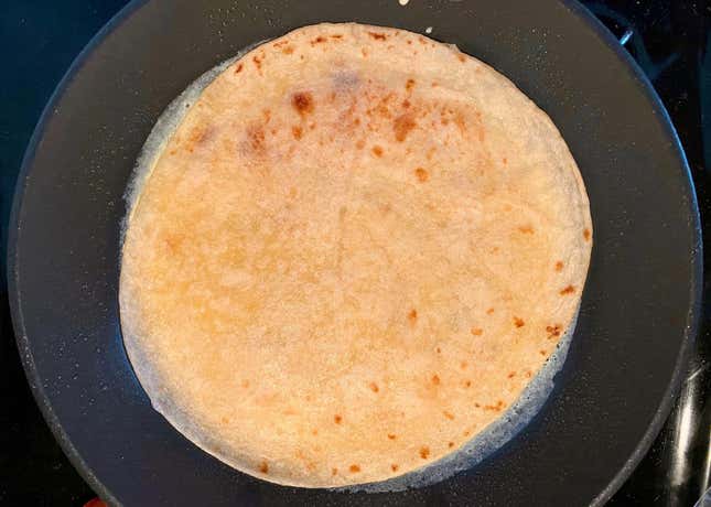 Tortilla in a frying pan, and added to the top of a thin omelette layer.