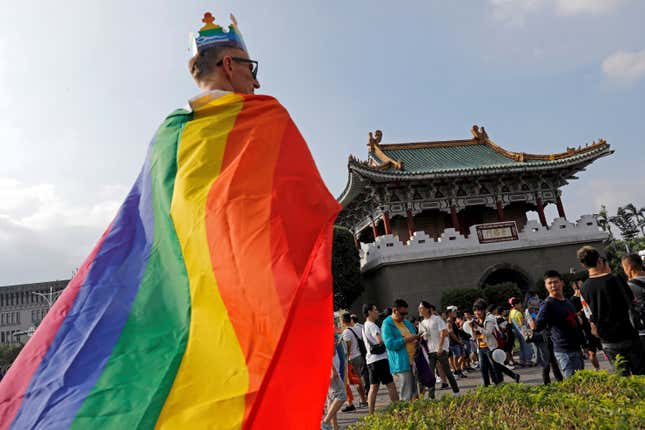 A participant is wrapped in a LGBT flag as he takes part in the pride parade in Taipei, October 28, 2017.