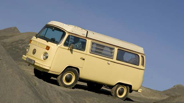A photo of a cream VW bus on a sand dune. 