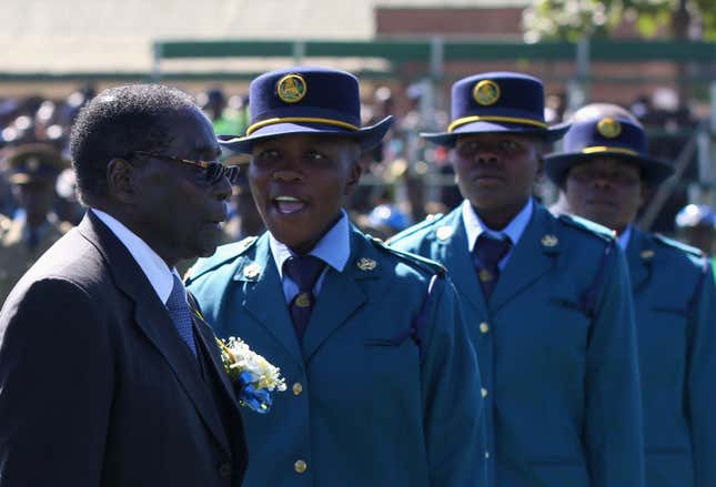 Zimbabwe’s President Robert Mugabe walks past police officers during a graduation ceremony in Harare May 29,2014.