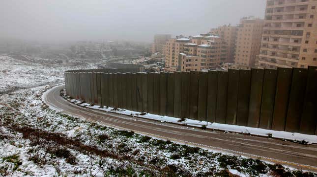 A partial view shows Israel’s controversial separation wall and the Palestinian Shuafat refugee camp following heavy snowfall in the Israeli-annexed eastern sector of Jerusalem, on February 18, 2021. 