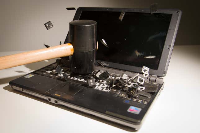 A laptop computer being smashed with a rubber mallet, its keys being flung every direction.