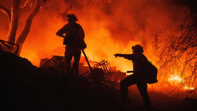 Firefighters coordinate efforts at a burning property while battling the Fairview Fire on Monday, Sept. 5, 2022, near Hemet, California. 