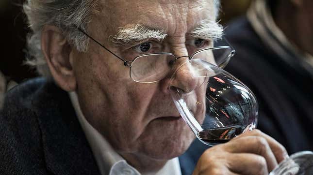 Older man looking concerned sniffing wine