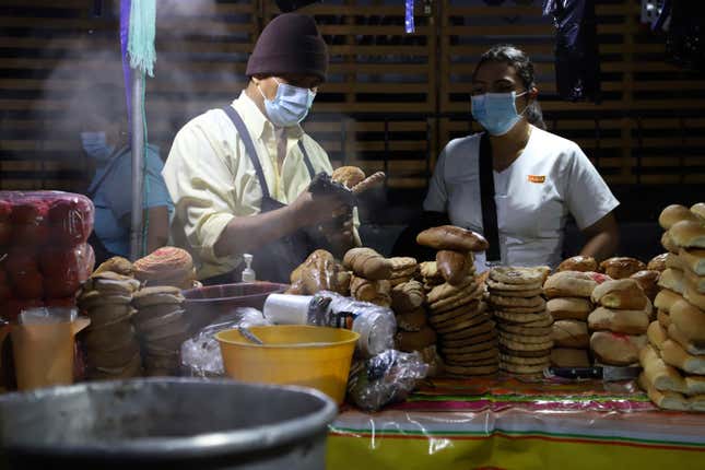 Miguel Menjivar, left, sells bread on a street in San Salvador, El  Salvador, before sunrise Tuesday, Sept. 7, 2021, on the day all  businesses have to accept payments in Bitcoin, except those lacking the  technology to do so.