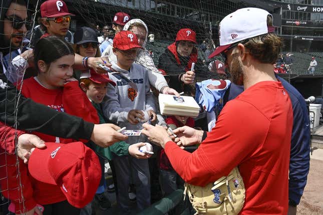 Apr 19, 2023; Chicago, Illinois, USA;   Philadelphia Phillies  Bryce Harper (right) signs autographs for young fans in the stands prior to the game against the Chicago White Sox at Guaranteed Rate Field.