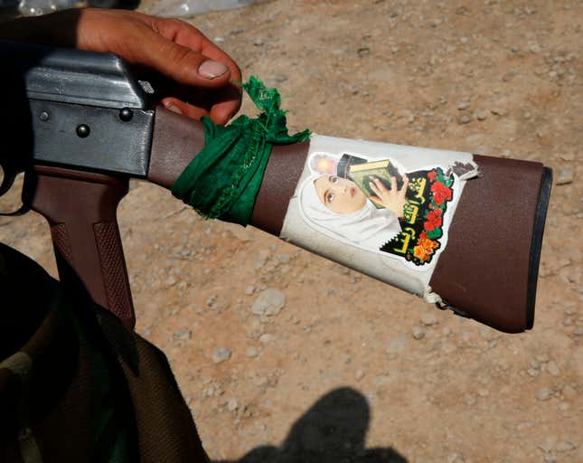 A fighter from the Shi'ite Badr Brigade militia shows a religious sticker on the stock of his AK-47 machine gun outside the town of Sulaiman Pek