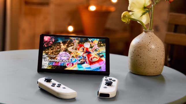 A Nintendo Switch OLED next to a vase.