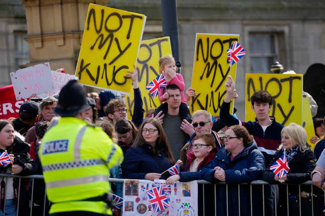 Protestors holding yellow signs that read "Not My King" wait for the arrival of King Charles III and Queen Camilla to visit Liverpool Central Library