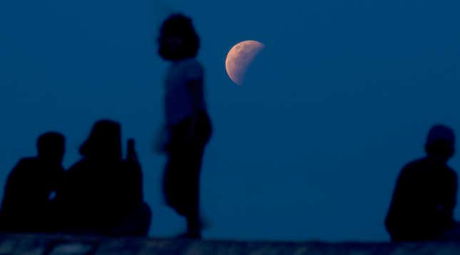 Residents watch the lunar eclipse at Sanur beach in Bali, Indonesia on Wednesday, May 26, 2021. 