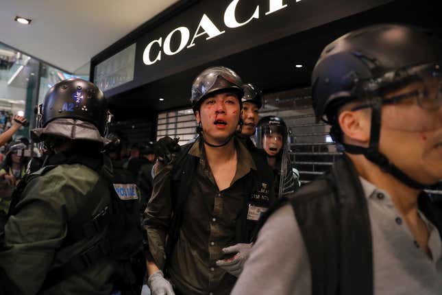 An injured policeman is escorted by his colleague after scuffles with protesters inside a mall in Sha Tin in Hong Kong, July 14, 2019.