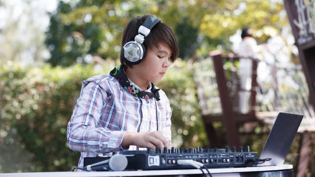 young child using a DJ soundboard, headphones and laptop