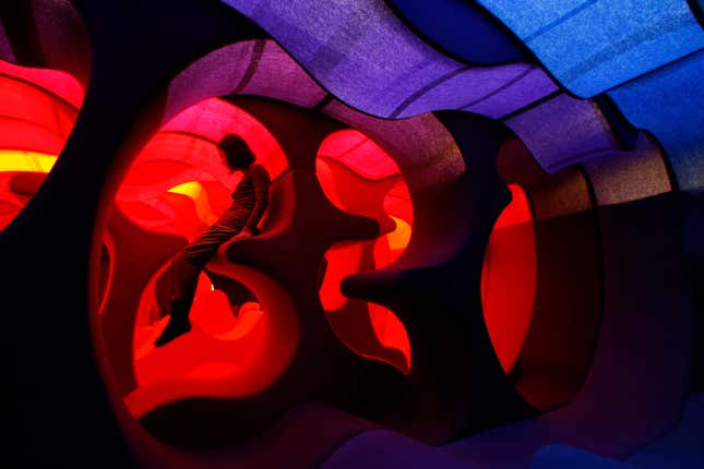 A visitor sits on Verner Panton's "Phantasy Landscape" which is made of fabric, wood and foam rubber, at the Tokyo Opera city art gallery in Tokyo November 26, 2009. The Danish designer and architect's exhibition goes on display until December 27. REUTERS/Kim Kyung-Hoon (JAPAN ENTERTAINMENT SOCIETY) - GM1E5BQ19EP01
