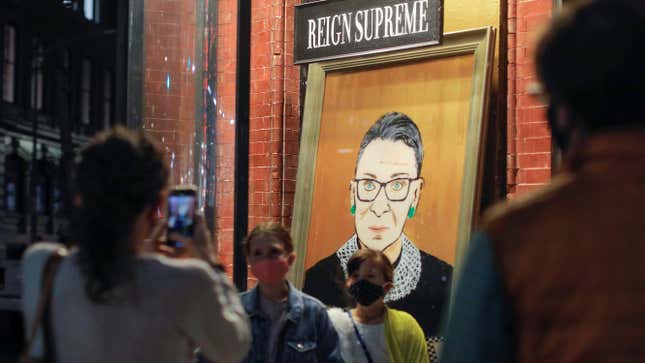 Children are photographed in front of a painting in a storefront on Broadway of Associate Justice of the Supreme Court of the United States Ruth Bader Ginsburg who passed away in Manhattan, New York City