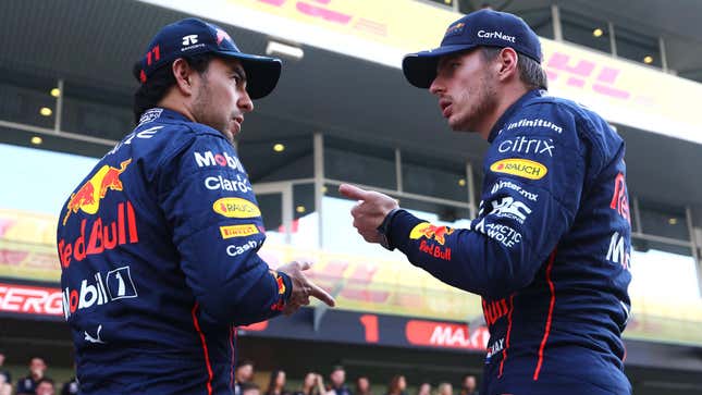 Sergio Perez and Max Verstappen talking with each other in front of their team's garage