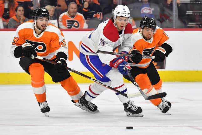 Mar 28, 2023; Philadelphia, Pennsylvania, USA; Montreal Canadiens center Jake Evans (71) battles for the puck against Philadelphia Flyers left wing Noah Cates (49) and defenseman Tony DeAngelo (77) during the first period at Wells Fargo Center.