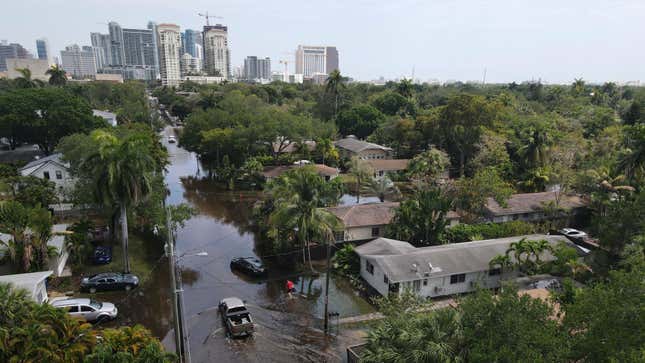 Trucks and a resident on foot make their way through receding floodwaters in the Sailboat Bend neighborhood of Fort Lauderdale, Florida on April 13, 2023.