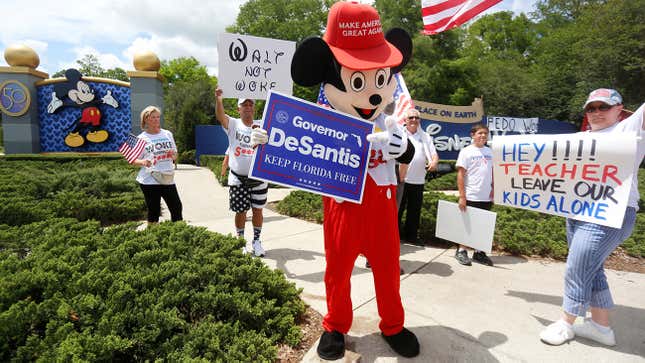 A person wearing a mouse costume holds a Governor Ron DeSantis poster stands where supporters of Florida’s Republican-backed “Don’t Say Gay” bill that bans classroom instruction on sexual orientation and gender identity for many young students gather for a rally outside Walt Disney World in Orlando, Florida, U.S. April 16, 2022. REUTERS/Octavio Jones