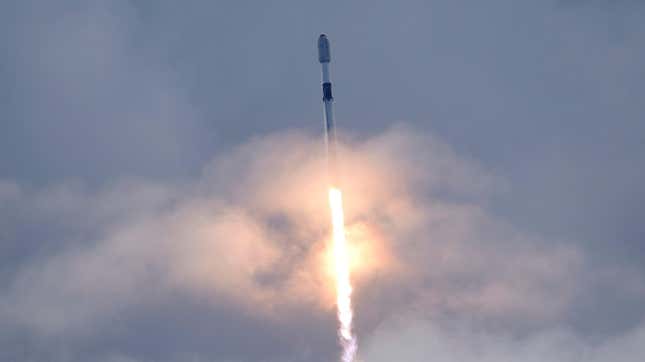 A falcon 9 rocket flies up into the clouds leaving behind a burst of fire and smoke.