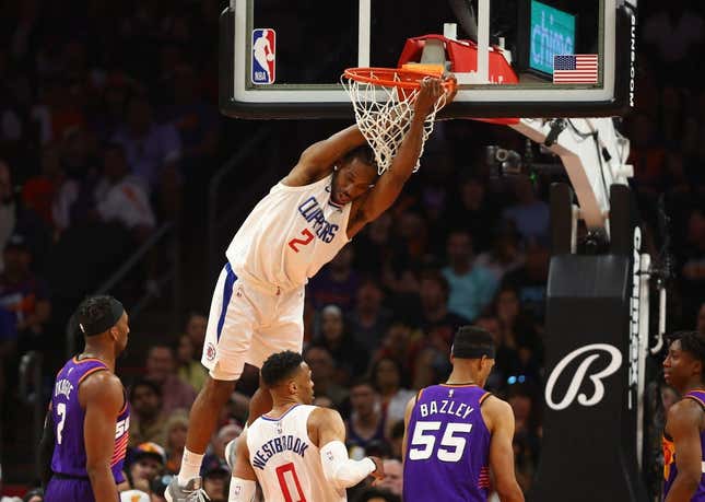 Apr 9, 2023; Phoenix, Arizona, USA; Los Angeles Clippers forward Kawhi Leonard (2) hangs from the rim after a slam dunk against the Phoenix Suns in the second half at Footprint Center.