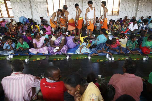 At a Sidi wedding, Brahmin temple workers feed Sidi wedding guests.