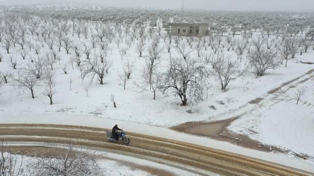  A Syrian man rides a motorcycle among groves covered with snow in the Jabal al-Zawiya region in the rebel-held northern countryside of Syria’s Idlib province, on Feb. 17, 2021.