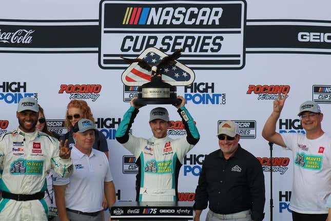 Denny Hamlin raises his trophy after winning the NASCAR Cup Series race at Pocono Raceway on Sunday, July 23, 2023.