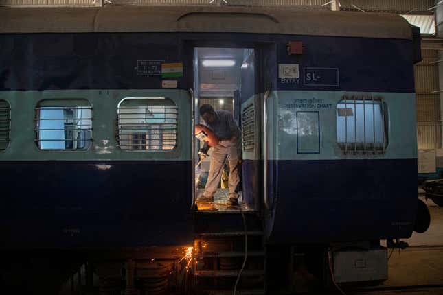An Indian Railways employee works to convert a train coach into an isolation ward.