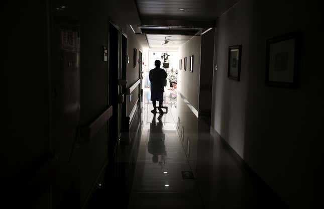 A cancer patient pushes his drip stand as he walks down the hallway of a hospital in Beijing