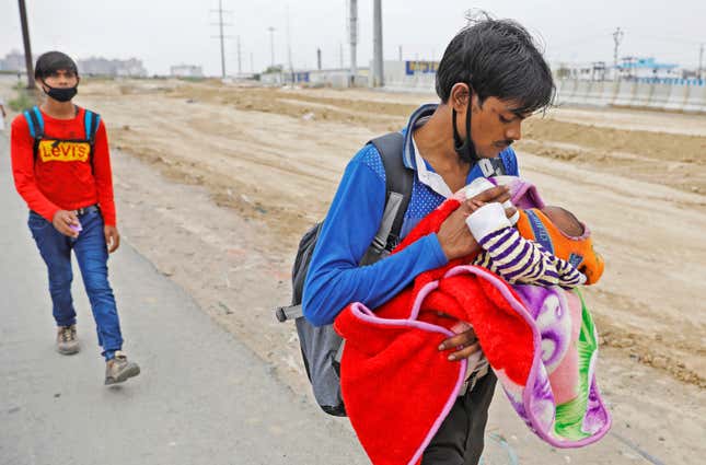 A migrant worker feeds his newborn baby as he walks on a highway on the outskirts of Delhi looking for a transport to return to his village.