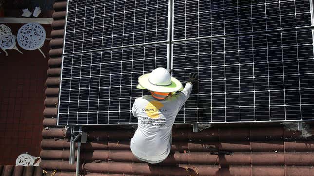 A worker installs a solar panel on a home in Palmetto Bay, Florida.
