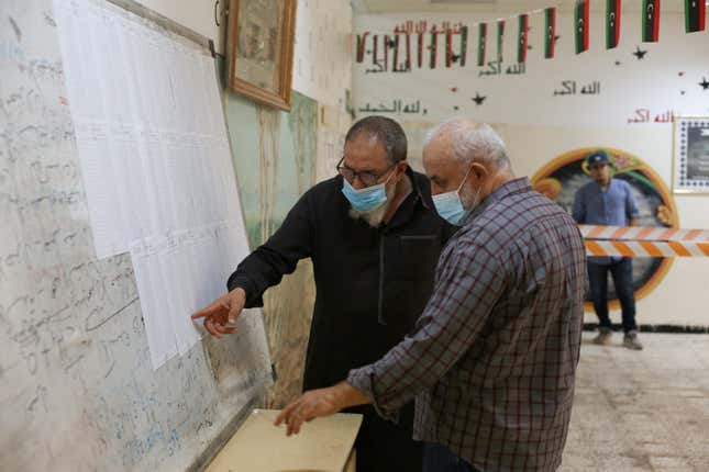 check names to receive their voter cards inside a polling station in Tripoli, Libya, November 8, 2021.