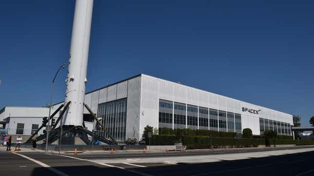 The SpaceX facilities in Hawthorne, California with a large rocket sitting outside on the main road. 
