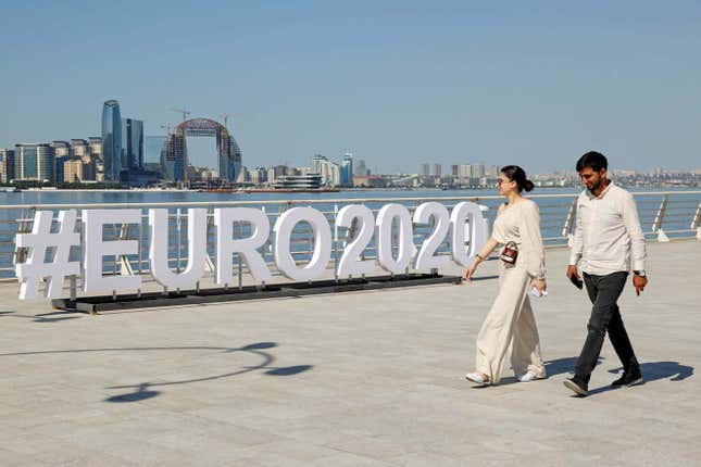 Two people walking by a big sign reading #EURO2020