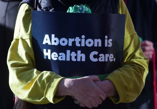 A woman holds a sign reading "abortion is health care"