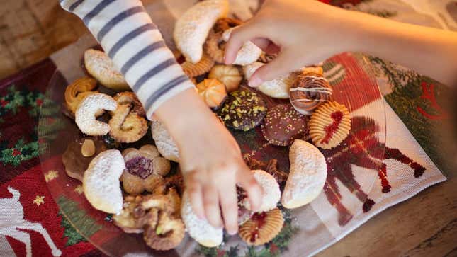 Children reaching for holiday cookies from platter