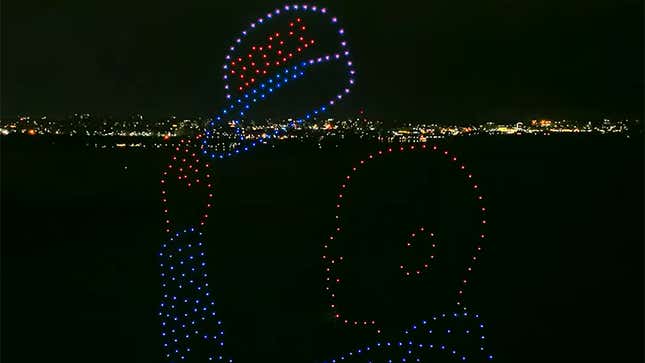 Drones taking the shape of a man holding a hat reading "2020" in front of the New York City skyline.