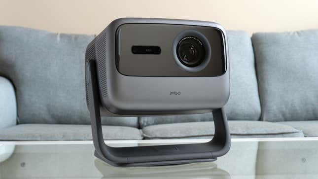 The JMGO N1 Ultra projector sitting on a coffee table in front of a sofa.