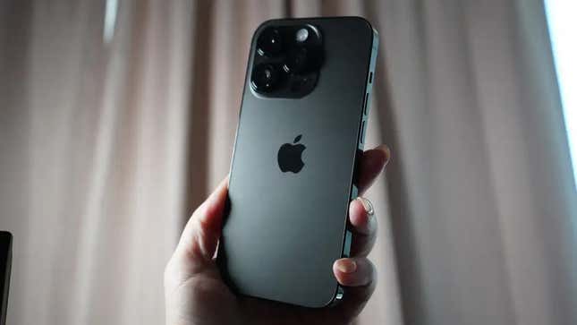An iPhone 14 pro held in hand amid a background. The iPhone with iOS 16 compatibility will be gaining new features soon.