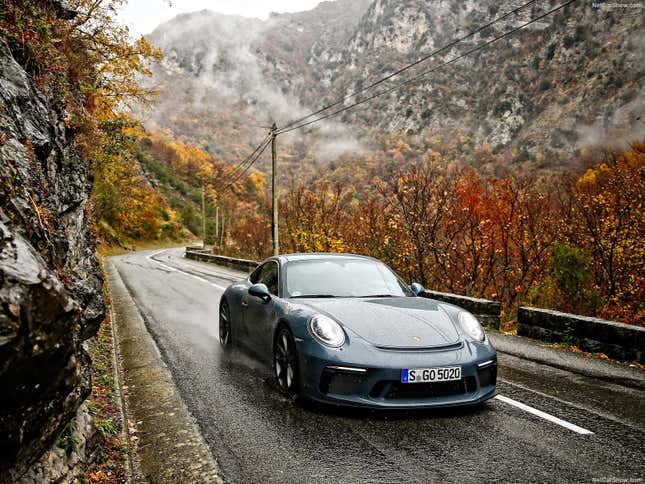 A slate blue 991.2 911 GT3 Touring drives a mountain road in the rain.