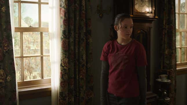 Ellie walks through Bill's house wearing a red shirt with a setting sun and palm trees.