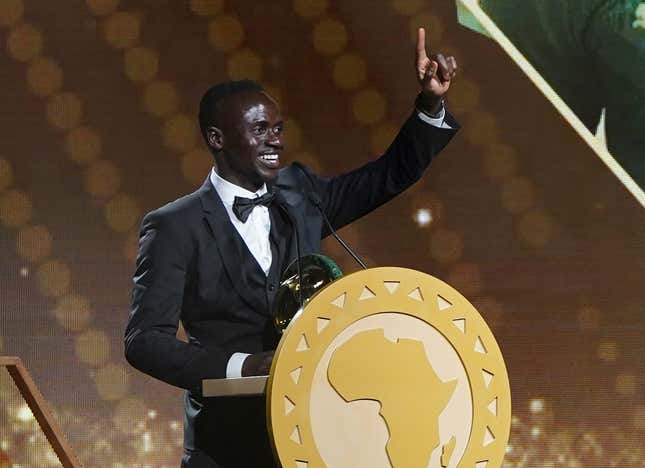 Sadio Mané on stage dressed in a black bow tie suit with his African Footballer of the Year award