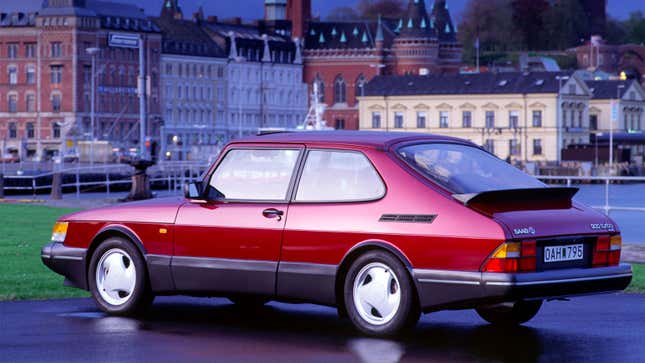 A photo of a red Saab 900 Turbo parked in a city. 