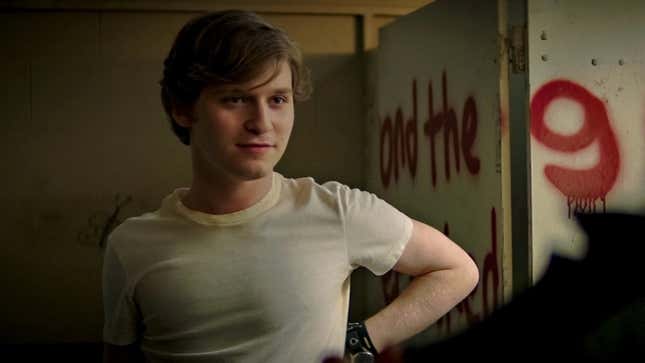 Fred Hechinger wears a while shirt in front of a wall with graffiti in a scene from Fear Street.