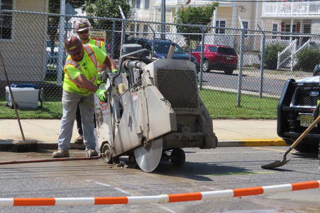 A worker uses an industrial cutting machine to open a section of the street in Ocean City, N.J. on Sept. 12, 2023, at the start of land-based probing along the right-of-way where a power cable for New Jersey&#39;s first offshore wind farm is proposed to run. Several protestors were arrested trying to block the work for the project being done by Danish wind energy company Orsted. (AP Photo/Wayne Parry)