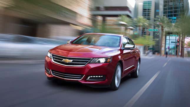 A red Chevrolet impala sedan driving on a street.