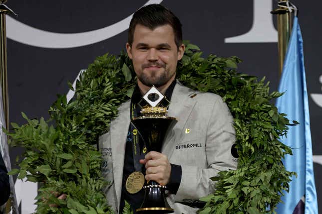 Magnus Carlsen stands with a trophy.