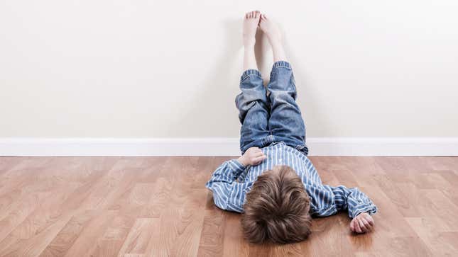 Child lying on floor with his feet on the wall