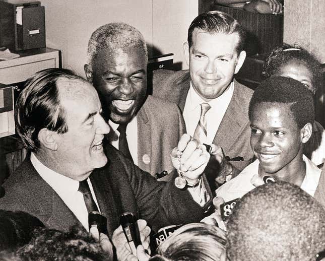 Hubert H. Humphrey, campaigning in Harlem to accept the endorsement of Jackie Robinson (behind him), displays a silver dollar key ring presented to him at the Freedom and National Bank August 14. Robinson, in his endorsement, said “For what it’s worth, I’m supporting Hubert Humphrey.”
