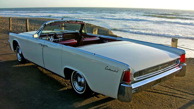A photo of a white Lincoln Continental convertible on a beach. 